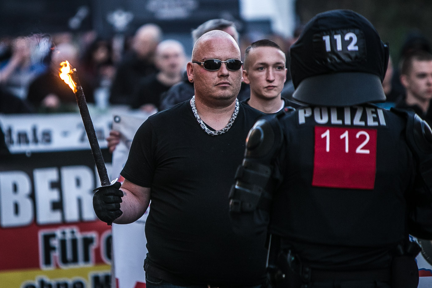 Un manifestant de la marxa de Thügida posa desafiant davant d’un agent antiavalot