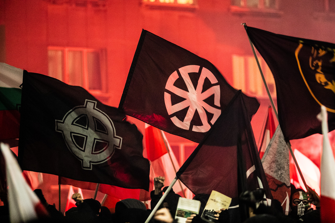 Una bandera neofeixista amb la creu celta i una amb el kolovrat entre el bloc més radicalitzat dels manifestants d’ultradreta