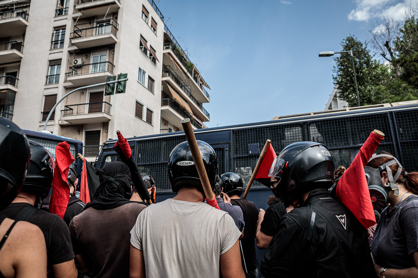 Manifestants protegits amb cascos i garrots davant del cordó policial